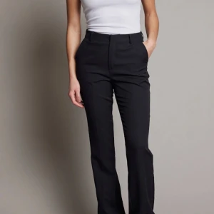 Svarta kostymbyxor - Snygga svarta kostymbyxor med hög midja och rak passform. Perfekta för en stilren look. Byxorna har en klassisk design med dragkedja och knappar framtill. Dem är uppsydda där nere men inget som syns. PRIS KAN DISKUTERAS