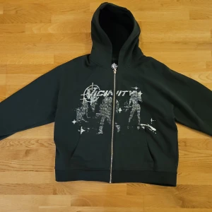 Grön hoodie från Vicinity - Säljer en grön hoodie från Vicinity med ett coolt tryck på framsidan. Tröjan har dragkedja och en bekväm huva, perfekt för en avslappnad stil. Passar bra till både jeans och joggers.