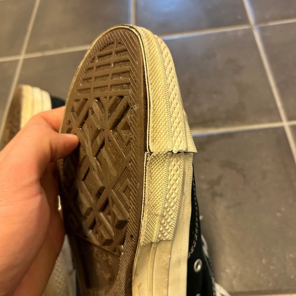 Säljer ett par svarta Converse sneakers med en röd hjärtdetalj på sidan. Skorna har vita snören och en klassisk gummisula. Perfekta för en avslappnad stil.. Kengät.