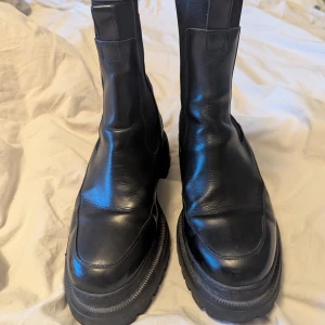 Svarta Chelsea Boots Arket  - Snygga svarta stövlar i skinn med robust sula och hög skaft, modell Chunky Chelsea Boots från Arket. Perfekta för höst och vinter med en stilren design. Väldigt sparsamt använda, fint skick! 