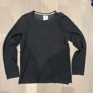 Elvine jumper - Säljer en stilren svart jumper från Elvine med ett subtilt sicksackmönster. Tröjan har långa ärmar och en rund halsringning. 