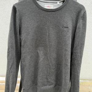 Grå stickad s.Oliver - Säljer en stilren grå stickad tröja från s.Oliver. Tröjan har en rund halsringning och är tillverkad i mjuk bomull. Perfekt för kyligare dagar.