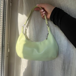 Ljusgrön axelväska - Snygg ljusgrön axelväska i syntetmaterial med stilren design. Väskan har en justerbar axelrem och stängs med dragkedja. Perfekt för att ge en färgklick till din outfit. Jättebra skick!! Perfekt storlek