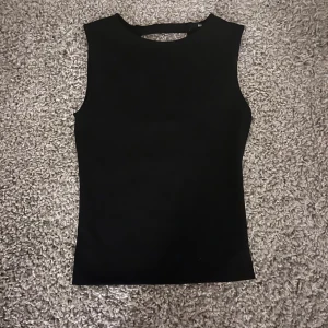 Svart festtopp - Snygg svart topp. Den har en stilren och tight passform med spännen på baksidan. Perfekt för en trendig look.
