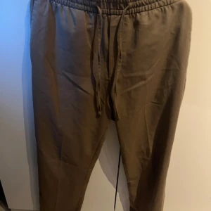 Bruna mjukisbyxor med snörning - Säljer ett par bekväma bruna mjukisbyxor med elastisk midja och snörning. Perfekta för en avslappnad stil.