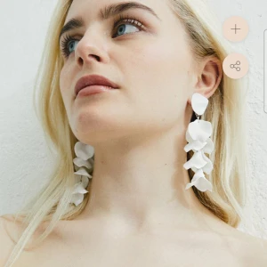 Flaket earrings white / örhängen vita - Säljer ett par  vita "flake"-örhängen från WOS. . Aldrig använda och kvar i originalpåsen. De har flera lager av blomblad som ger en elegant och iögonfallande look. Den som önskar en mer diskret framtoning kan häktad av halva längden (se bild). Perfekta för att lyfta vilken outfit som helst! 