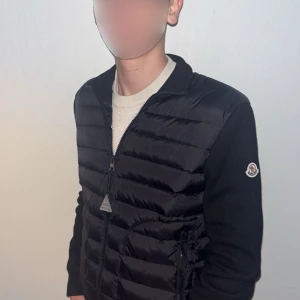 Svart cardigan från Moncler - Snygg svart cardigan från Moncler med dragkedja och långärmade ärmar. Jackan har ett stilrent märke på ärmen och är perfekt för kyligare dagar. Säljer pga den är för liten och pris går självklart ner vid snabbaffär.