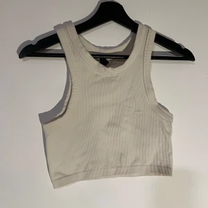 Vit ribbad linnetopp - Snygg vit ribbad linnetopp med breda axelband. Perfekt för varma dagar eller som ett lager under en jacka. Enkel och stilren design som passar till det mesta.