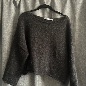 Mörkgrå tröja från Zara - Säljer en mysig mörkgrå tröja från Zara. Tröjan har en lös passform och är långärmad, perfekt för kyligare dagar. Den är tillverkad i ett mjukt material som ger en skön känsla. Passar bra till både jeans och kjol.