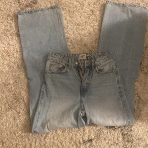 Ljusblå jeans med slitningar - Säljer ett par ljusblå jeans från 157 med en cool sliten look. De har en klassisk femficksdesign och en stor reva på båda benen för en trendig stil. Perfekta för en avslappnad outfit.