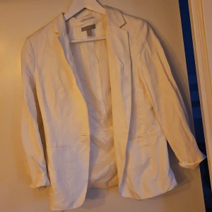 Vit kavaj - Snygg vit kavaj med klassisk design. Perfekt för att ge en stilren look. Kavajen har långa ärmar och en elegant passform. Ett måste i garderoben för den som vill ha en tidlös stil.