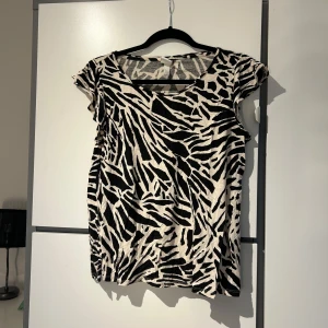 Zebramönstrad topp - Snygg zebramönstrad topp med korta ärmar och rund halsringning. Materialet är mjukt och bekvämt.