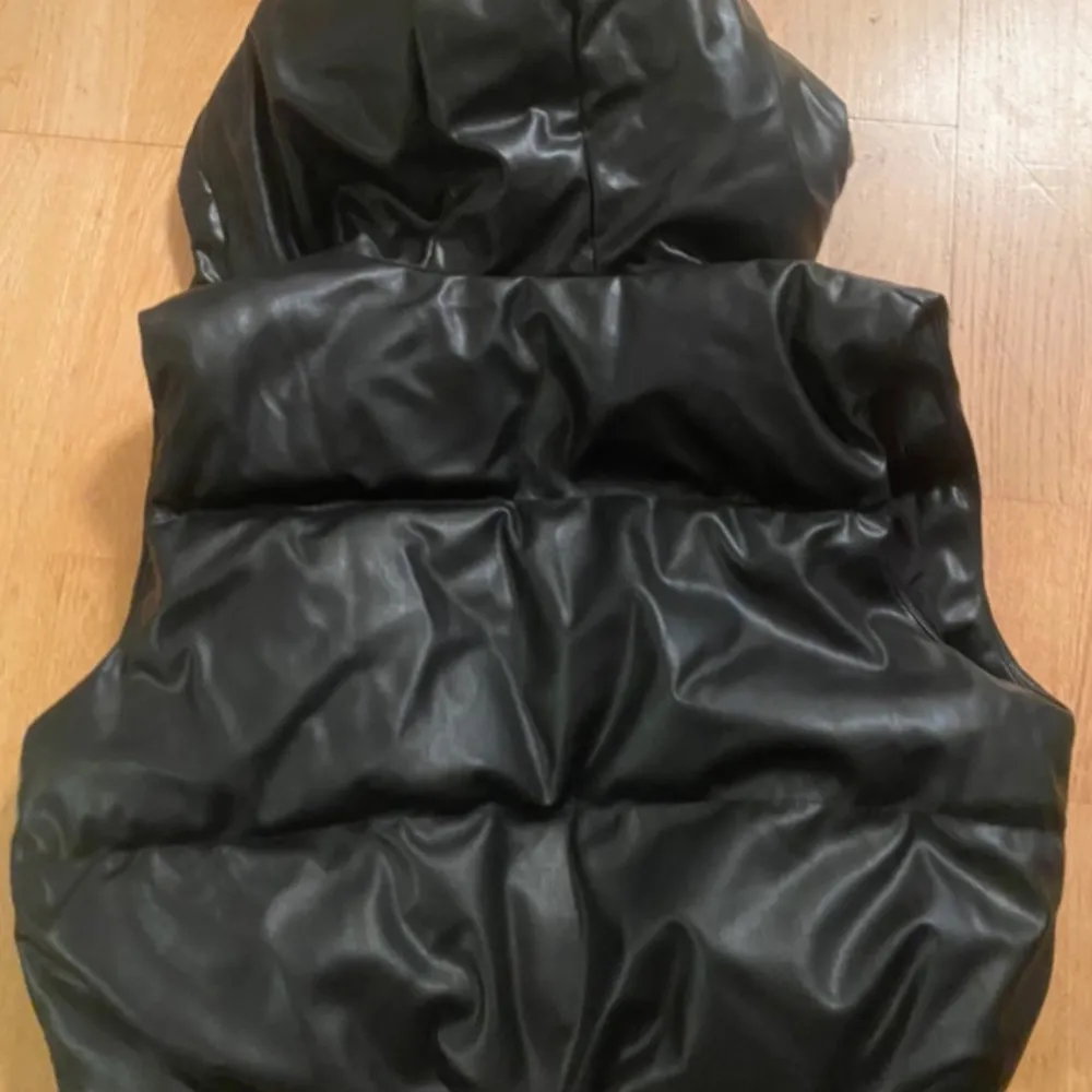 Snygg svart väst från H&M Divided med huva och dragkedja. Perfekt för lager-på-lager-stil under kyligare dagar. Västen har en modern look och är lätt att matcha med olika outfits.. Takit.
