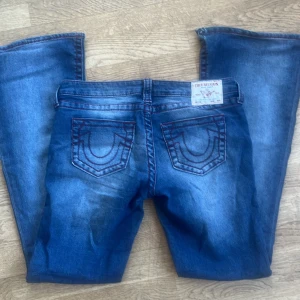 Blå jeans från True Religion - Snygga blå jeans från True religion med sömmar i rött.  De är bootcut och en låg midja. Helt nya, använda en gång. 