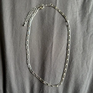 Silverfärgat halsband med länkar - Elegant silverfärgat halsband med rektangulära länkar och justerbar kedja. Perfekt för att lägga till en stilren touch till din outfit. EJ ÄKTA!!