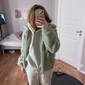 Grön teddyjacka från Bubbelroom - Mysig grön teddyjacka från Bubbelroom med dragkedja framtill och stora fickor. Perfekt för kyliga dagar när du vill vara både varm och stilren. Jackan har en fluffig textur och en bekväm passform. Använd ca 2 gånger köptes för 499!😇