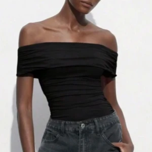 Svart offshoulder topp - Snygg svart offshoulder topp med tight passform. Perfekt för en stilren look. Tillverkad i ett mjukt och stretchigt material som sitter bekvämt.