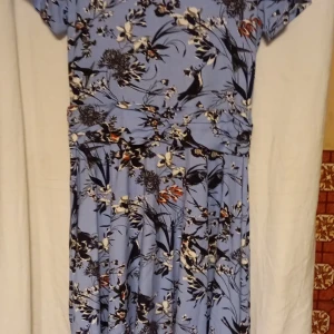 Blommig klänning från Fransa - Säljer en vacker ljusblå klänning från Fransa med fåglar och blommönster. Klänningen har korta ärmar och är tillverkad i ett mjukt material av viskos och elastan för en bekväm passform. Perfekt för en somrig look! 🌸