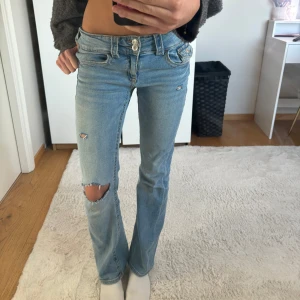 Ljusblå jeans med slitningar - Snygga ljusblå jeans från Gina Tricot med slitningar på knäna och låren. De har en klassisk femficksdesign och knappgylf. Jag har gjort hålen själv men de blev bra och inga defekter påkom! Orginal pris: 359kr💝 midjemått-37cm innerbenslängd- 78cm💘