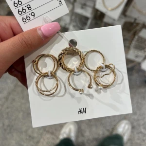 Guldiga ringar - Ett set med flera guldiga ringar från H&M. Ringarna har olika design, inklusive en med en liten pärldetalj och en med tvinnad struktur. Perfekt för att mixa och matcha för olika stilar. Storlek XS