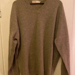 Beige kashmirtröja från EWM - Säljer en stilren beige kashmirtröja från EWM. Tröjan har en v-ringad hals och långa ärmar, perfekt för kyliga dagar. Den är mjuk och bekväm, vilket gör den till ett måste i garderoben. Passar bra till både jeans och kjol.