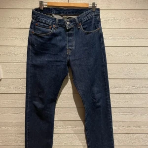 Levis 501 jeans - Klassiska Levis 501 jeans i mörkblå denim. De har en rak passform och knappgylf. Perfekta för en tidlös stil med fem fickor och den ikoniska Levis-lappen baktill.