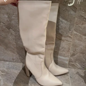 Beige stövlar med klack - Snygga beige stövlar i syntetmaterial med spetsig tå och klack. Perfekta för en stilren look.