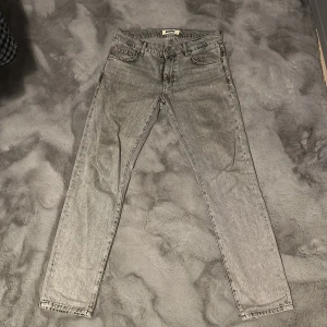 Grå jeans från Woodbird - Snygga grå jeans från Woodbird med klassisk femficksdesign. De har en rak passform och är perfekta för en avslappnad stil. Jeansen har en knappgylf och bälteshällor.