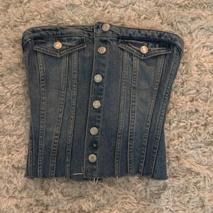 Jeans korsett från Zara - Säljer en cool jeans korsett från Zara med knappar framtill och två dekorativa fickor. Säljer då den inte kommer till användning längre💙