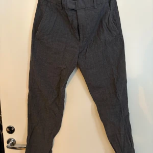 Grå kostymbyxor - Snygga grå kostymbyxor med en klassisk passform. De har en midwaist design och är perfekta för en stilren look. Byxorna har diskreta fickor och en dragkedja framtill. Storlek us 32r