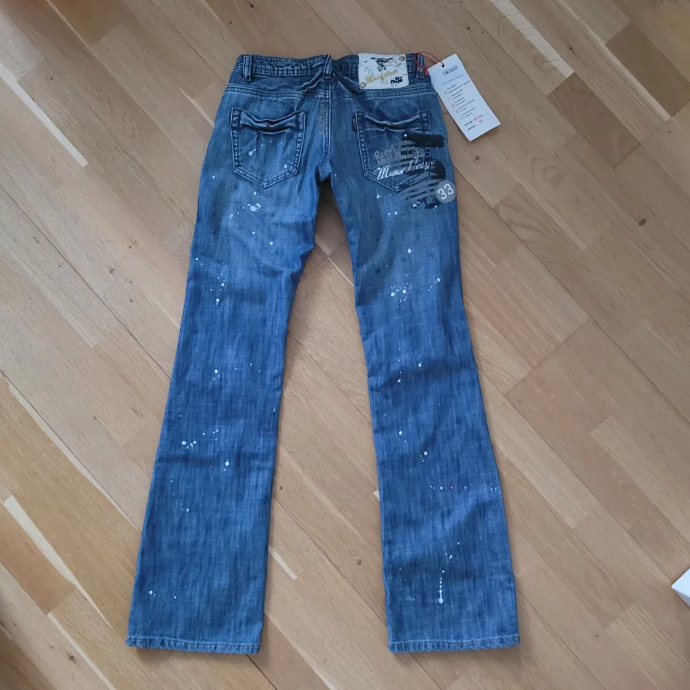 Snygga blåa bootcut jeans från Musketeer med unika detaljer och stänkdesign i storlek W26. De är helt nya med lappar kvar! Om ni har några funderingar är det bara att fråga🩷 Tyvärr är de för små för mig så kan inte skicka bild med dem på. Midja: ca. 34. Innerbenslängd: ca 83 cm.. Farkut & Housut.