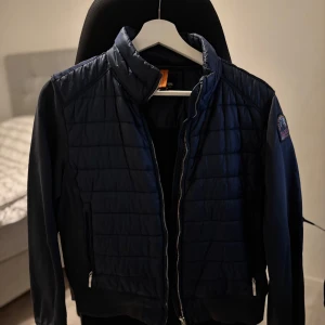 Mörkblå jacka från Parajumpers - Säljer en mörkblå jacka från Parajumpers med quiltad design och dragkedja. Jackan har en snygg logga på ärmen och är tillverkad i fleece för extra värme. Perfekt för kyligare dagar. Storlek M till barn. Ny pris 3500