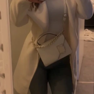 Vit kappa med knytband - Elegant vit kappa med knytband i midjan. Perfekt för en stilren look. Långärmad design som passar bra till våren nu nypris 599kr