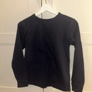 Svart långärmad tröja från C - Säljer en enkel och stilren svart långärmad tröja från märket C. Perfekt för en avslappnad look. Tröjan har en rund halsringning och är tillverkad i ett mjukt material.