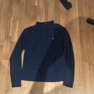 Mörkblå pikétröja från Ralph Lauren - Säljer en stilren mörkblå pikétröja från Ralph Lauren. Storleken motsvarar typ xs/s herrstorlek men är stretchig. Den är lite kort på mig som är 183. Priset är inte hugget i sten!