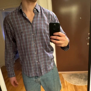 Rutig skjorta från Ralph Lauren - Säljer en klassisk rutig skjorta från Ralph Lauren i blått, vitt och rött. Skjortan har långa ärmar och knappar framtill. Perfekt för en stilren look till sommaren. Passar bra att ha innanför som utanför brallan. Skick 9/10 storlek M/L