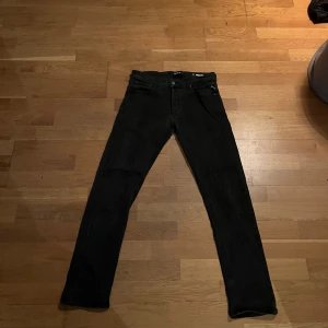  jeans från Replay - Snygga svarta/gråa jeans från Replay med klassisk femficksdesign. De har en knappgylf och är tillverkade i ett slitstarkt material. Perfekta för en stilren look.