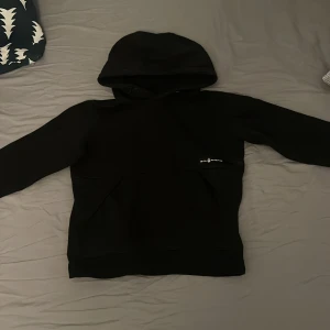 Svart hoodie från Sail Racing - Säljer en stilren svart hoodie från Sail Racing. Tröjan har en klassisk design med en stor huva och långa ärmar. Perfekt för en avslappnad look. 🖤