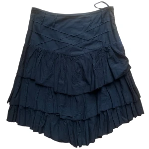 Svart volangkjol från Vila - Snygg svart kjol från Vila med flera lager av volanger som ger en härlig volym. Kjolen har en omlott-design upptill och är perfekt för att skapa en chic look. Den är i storlek XL på lapp men skulle säga mer passar en S eller M