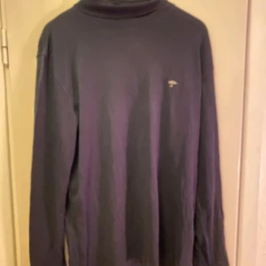 Svart polotröja från Fynch-Hatton - Säljer en stilren svart polotröja från Fynch-Hatton i Supima bomull. Tröjan har långa ärmar och en diskret logga på bröstet. Perfekt för en elegant och bekväm look.