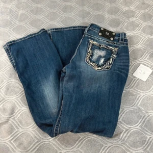 Miss me jeans - Snygga blå jeans med unika broderade detaljer på bakfickorna. De har en bootcut-stil och en klassisk femficksdesign. Perfekta för en avslappnad look med en touch av stil.