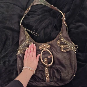 Guess 2000s väska🎀 - Äkta Guess väska med 2000s stil. Väldigt rymlig med snygga detaljer och även en innerficka i väskan & en ficka på baksidan. I fickan på baksidan har det tyvärr blivit spår med bläck som man kan se på sista bilden💗