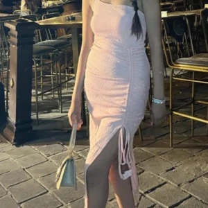 Rosa axelbandslös klänning - Snygg rosa axelbandslös klänning med knyt och slits framtill. Perfekt för en utekväll eller fest. Klänningen har en tight passform som framhäver figuren.