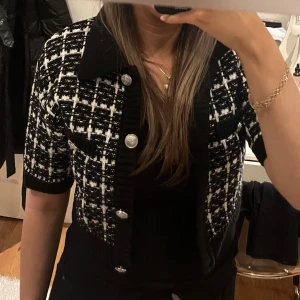 Svartvit rutig kofta med knappar - Kort Snygg svartvit rutig kofta med korta ärmar och stora dekorativa knappar. Slutsåld i butik! 