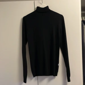 Svart polotröja från Collusion - Säljer en stilren svart polotröja från Collusion. Den är helt oanvänd och i skönt ylle. Tröjan har en klassisk design med långa ärmar och en hög krage. Perfekt för att hålla sig varm och snygg under kyligare dagar. Passar bra till både jeans och kjol. Skriv direkt vid minsta frågetecken!