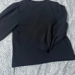 Svart tröja från 157 - En snygg tröja från 157 med långa ärmar och rund halsringning. Perfekt för en stilren look. Tröjan har en enkel design som gör den lätt att matcha med olika outfits.