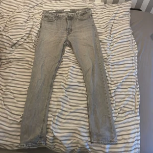 Grå jeans från Jack & Jones - Säljer ett par grå jeans från Jack & Jones med en loose passform. Modellen heter Chris och har en klassisk femficksdesign. Perfekta för en avslappnad stil.  Bredd:30   Längd:34