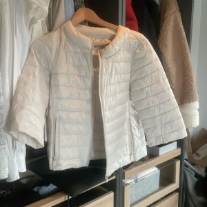 Vit trekvartsärmad jacka från Monte Cervino - Säljer en stilren vit jacka från Monte Cervino. Jackan har trekvartsärmar och en dragkedja framtill. Perfekt för för våren när du vill hålla stilen enkel och snygg.