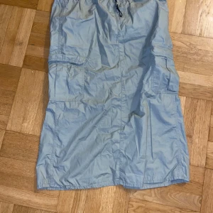 Ljusgrön kjol med fickor - Säljer en ljusgrön midikjol med praktiska fickor på sidorna och en bekväm passform. Kjolen har en slits baktill och är perfekt för en avslappnad stil. Den är tillverkad i ett lätt material som passar bra för varmare dagar.