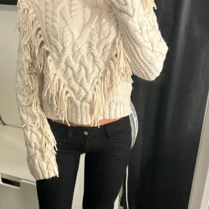 Vit stickad tröja med fransar - Superfin och unik stickad tröja. Den är från hm och köpt för länge sen. Den är dock knappt använd och är derför i nyskick. Den har fransar längs ärmarna och fram på sidan av magen typ. 